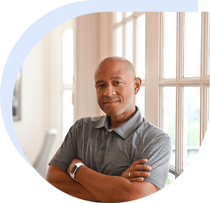 Smiling bald man standing by sunlit window