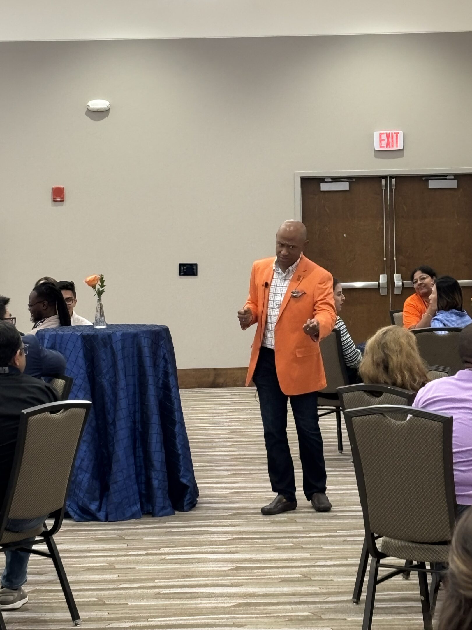 Man in orange blazer speaking to audience